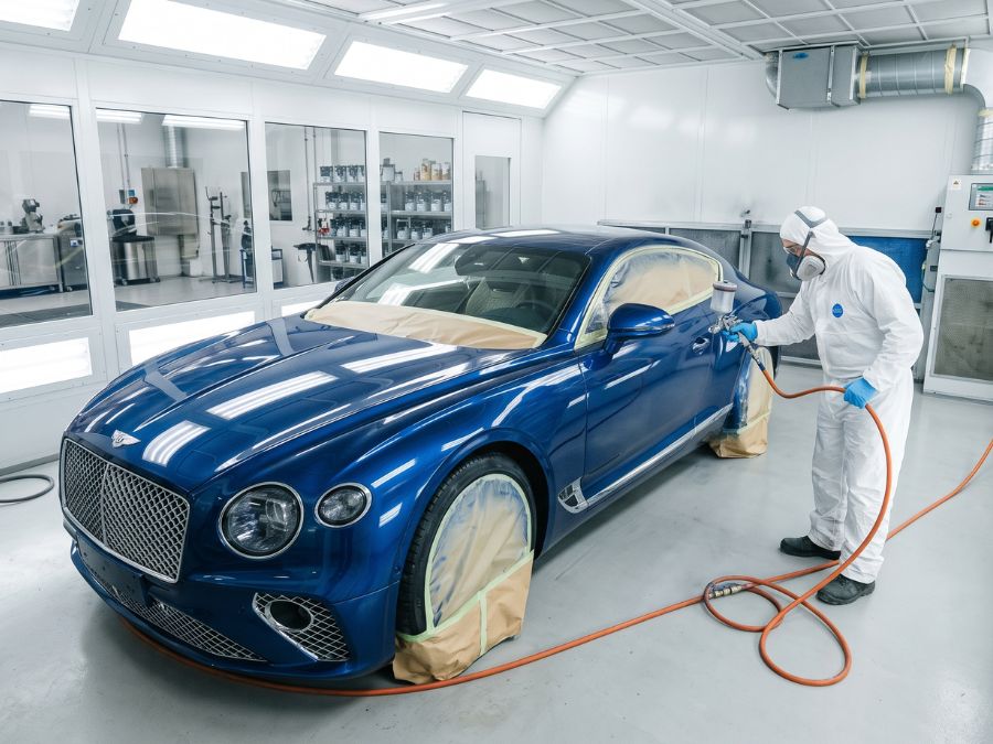 Luxury car receiving professional car painting services in a Dubai paint booth